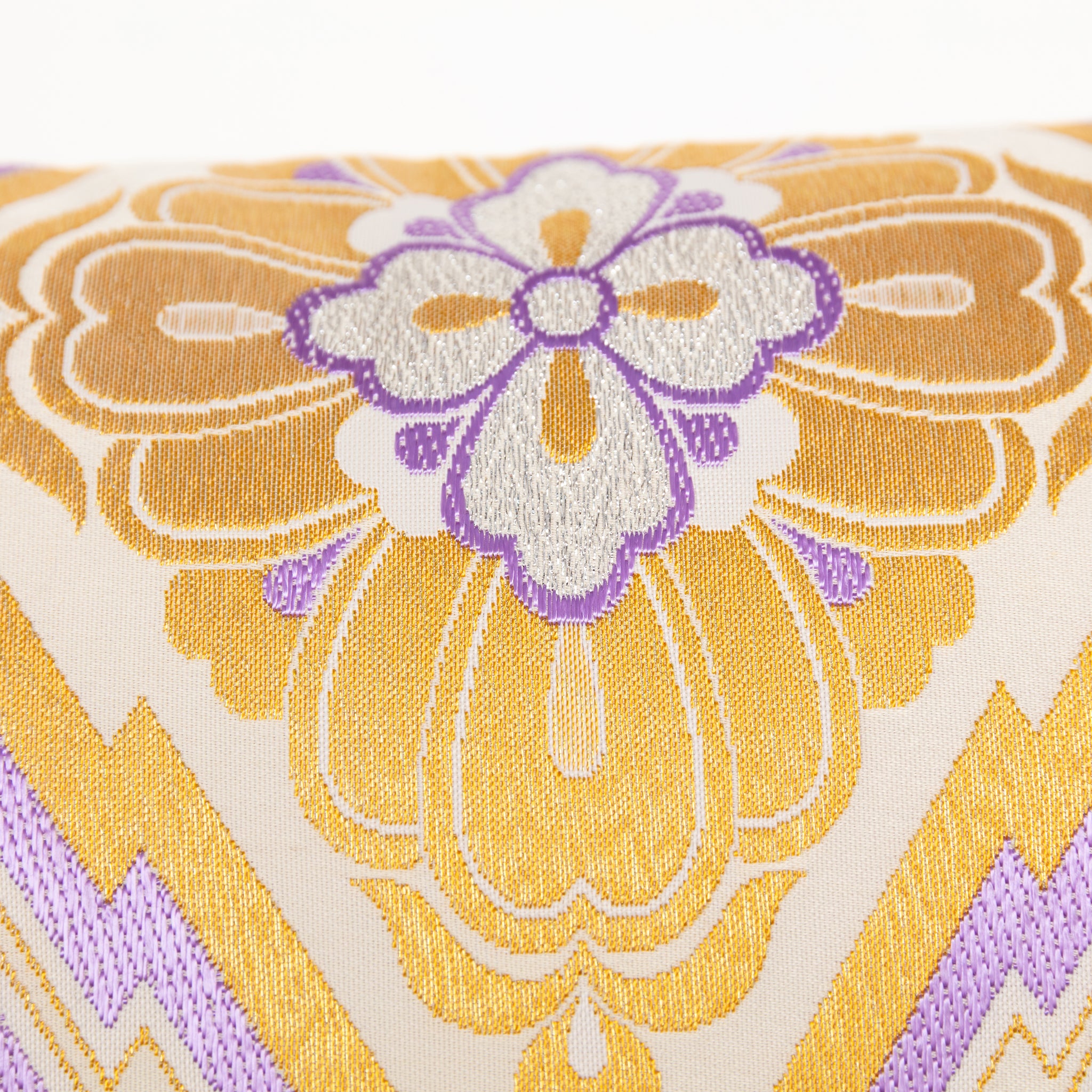 Detail of metallic gold embroidery and purple silk thread weaving on a vintage Japanese obi cushion.