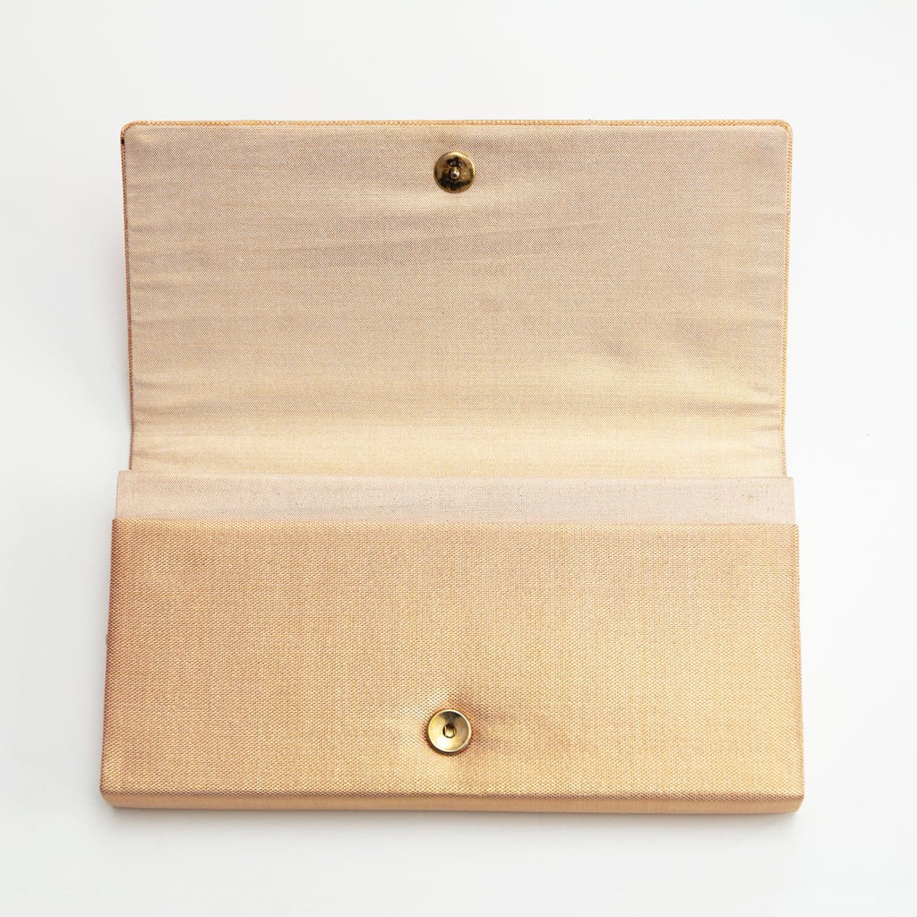 Gold vintage silk envelope clutch bag with the flap open to show the silk lining inside and the metal fastener. 