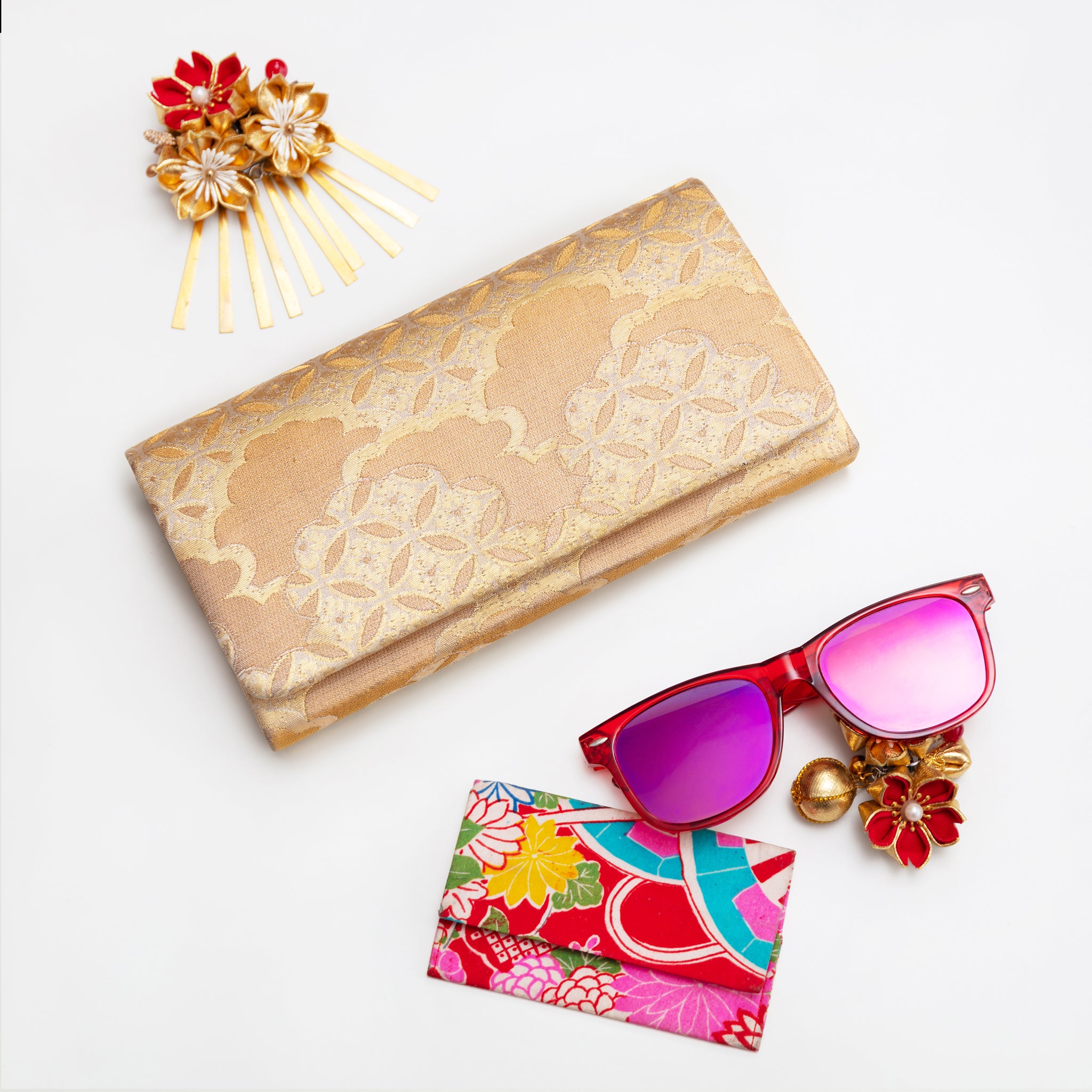 Vintage gold textured kimono silk bag with Japanese shippo pattern on a white background with sunglasses and accessories around it.