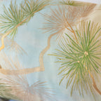 Close-up of pine branches across pale blue and beige vintage fukuro obi silk