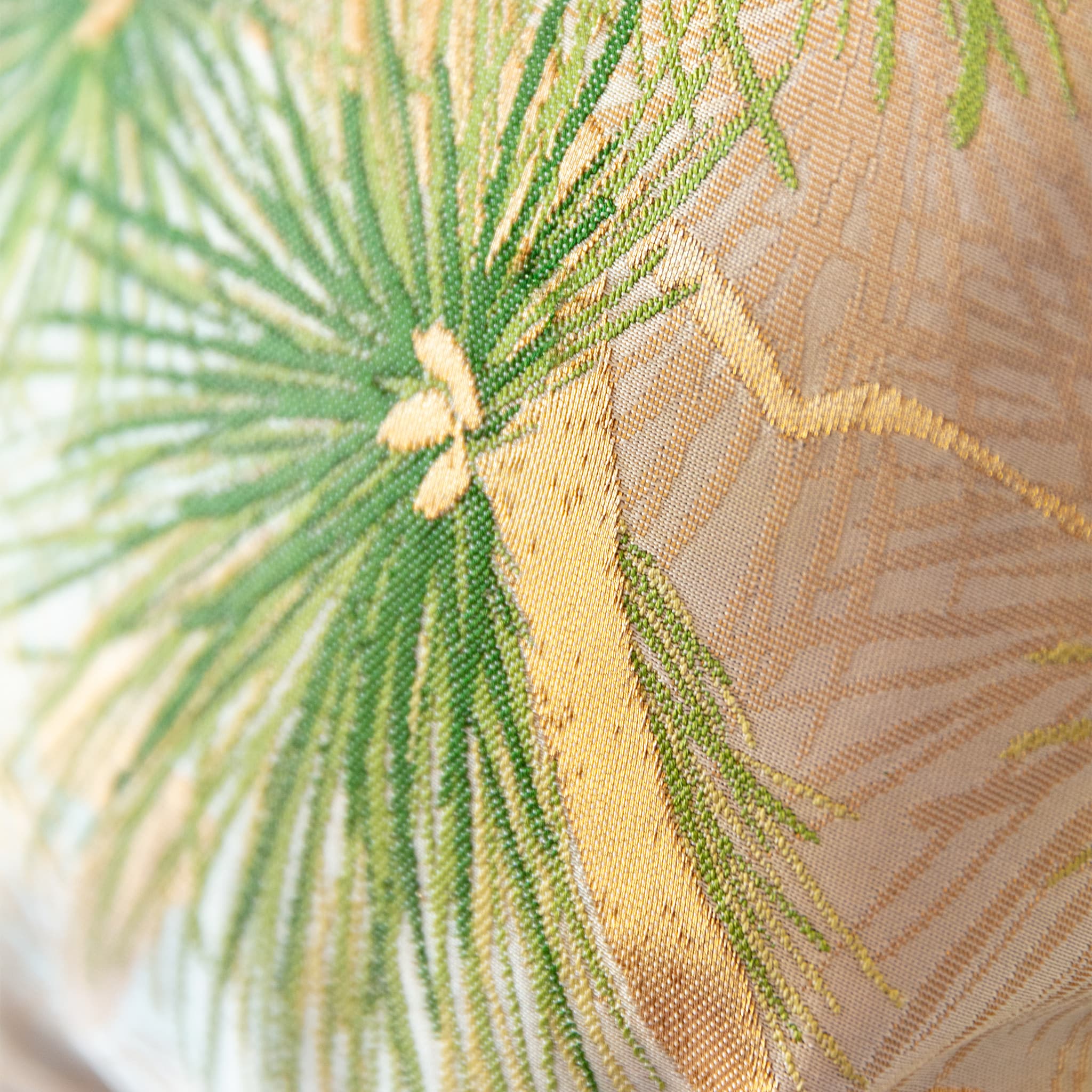 Close-up of woven green pine needles and gold detailing on vintage fukuro obi silk