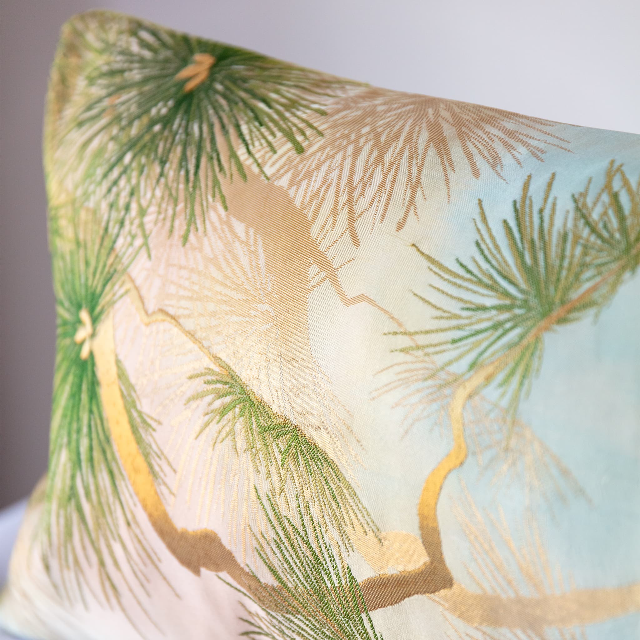 Corner detail of vintage fukuro obi silk cushion with metallic gold pine trunk and green pine needles