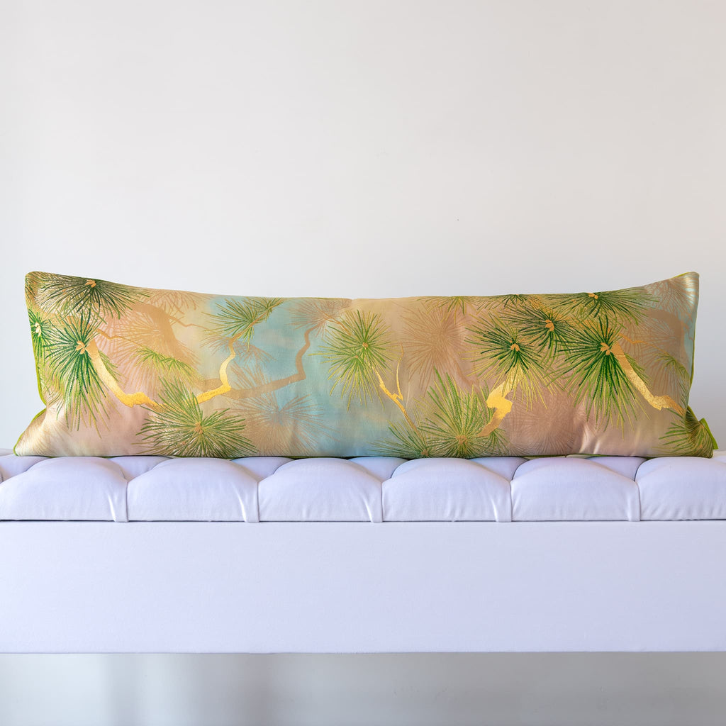 Green silk bolster cushion made from vintage Japanese fukuro obi with pine tree motifs on a white bench