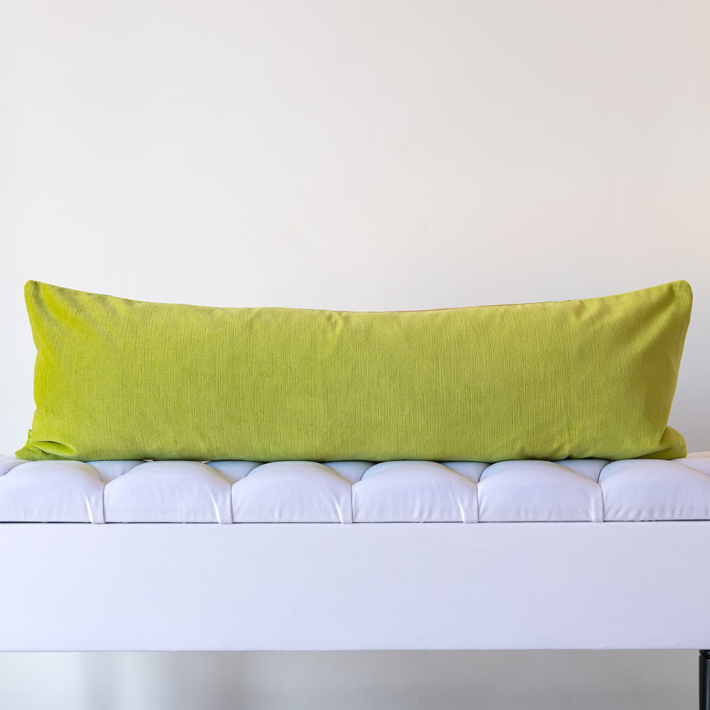 Reverse of green silk bolster cushion in sage green velvet on a white bench