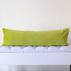 Reverse of green silk bolster cushion in sage green velvet on a white bench