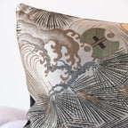 Corner detail of grey silk bolster cushion showing woven Maru Obi textile with pine and wild wave motifs