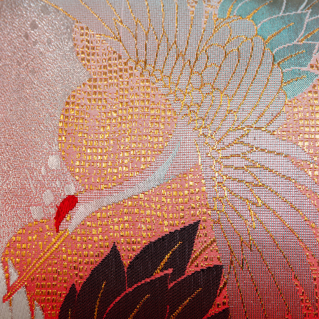 Close-up of the red silk and taupe velvet fabric combined with detailed stitching on the bolster pillow's corner.