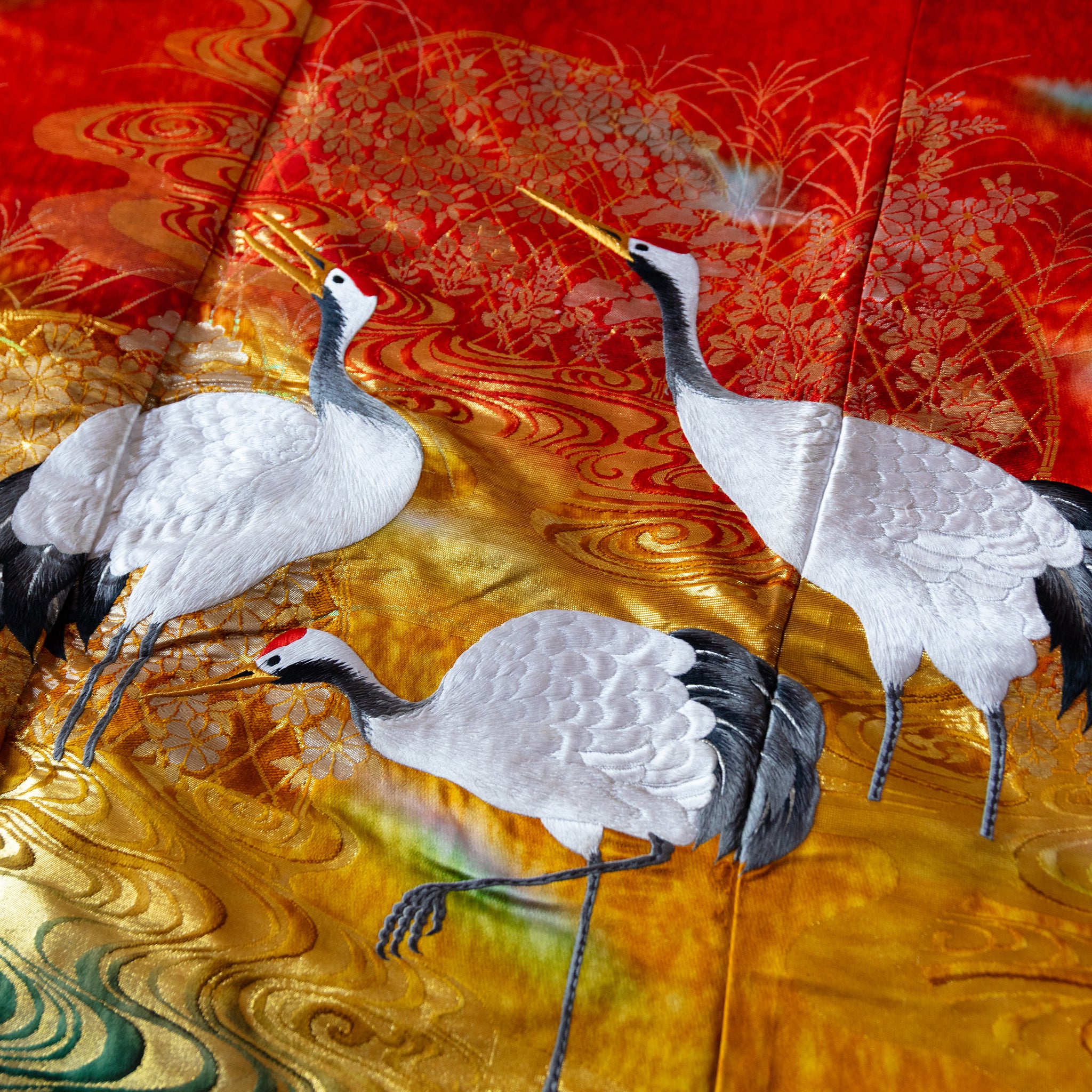 detail of vintage kimono silk throw of three white embroidered cranes over red and gold