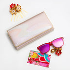 Pink and silver vintage Japanese silk clutch bag with gold trim on white surrounded by accessories.