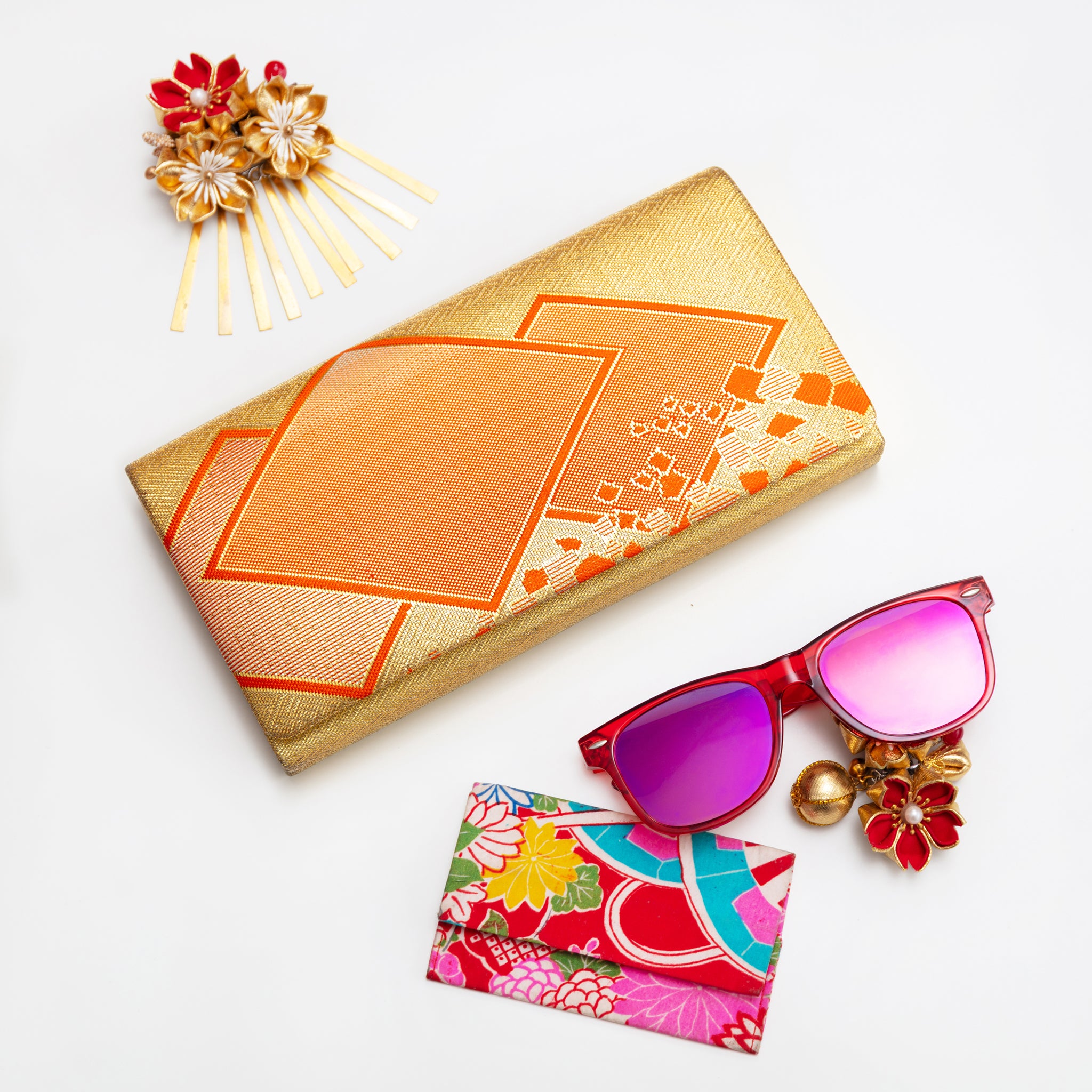 Vintage Japanese kimono silk envelope clutch bag in gold with orange geometric accents on a white background with accessories.