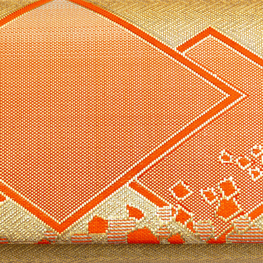 Close up vintage kimono silk brocade with metallic gold weave and orange silk geometric diamond shapes.