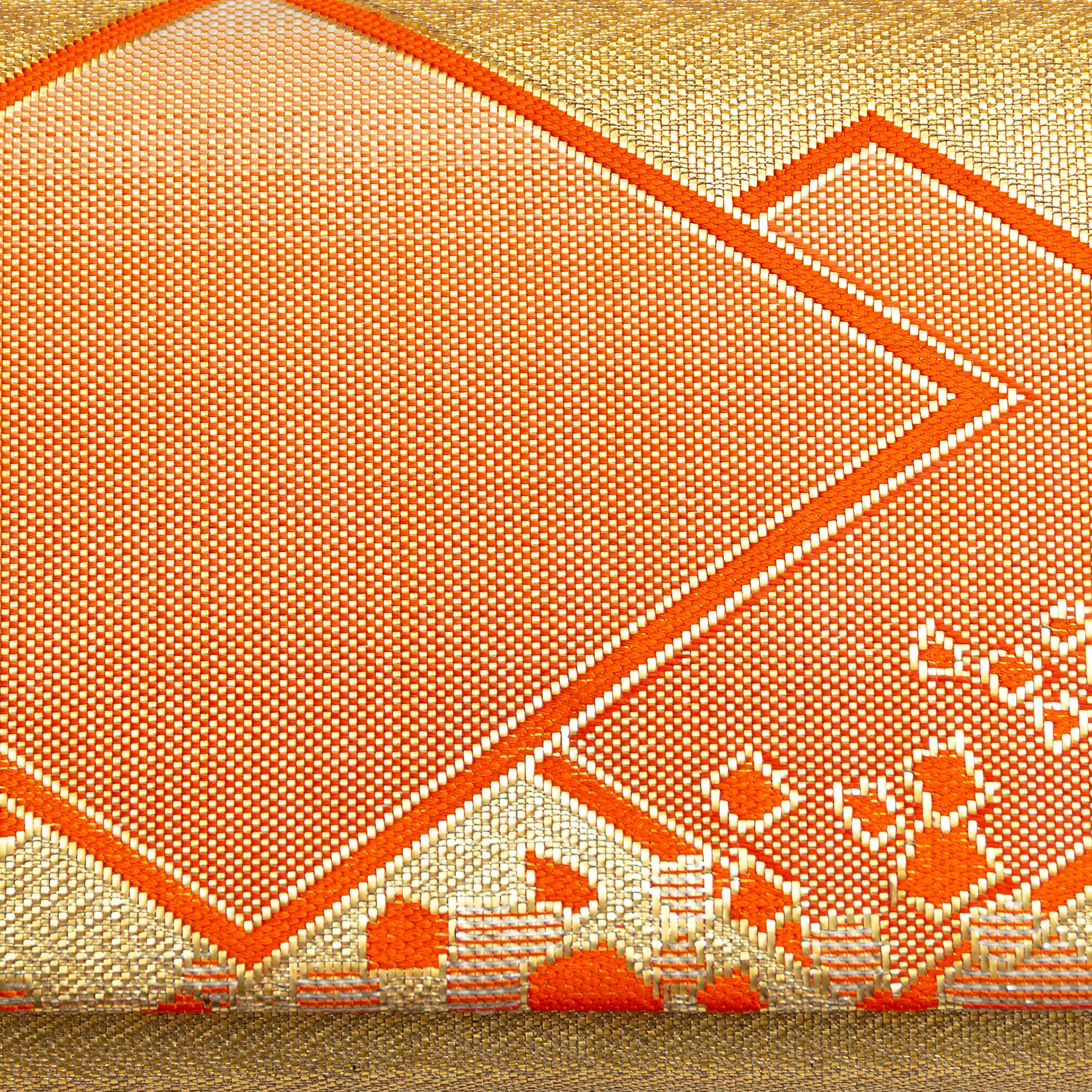 Close up vintage kimono silk brocade with metallic gold weave and orange silk geometric diamond shapes.