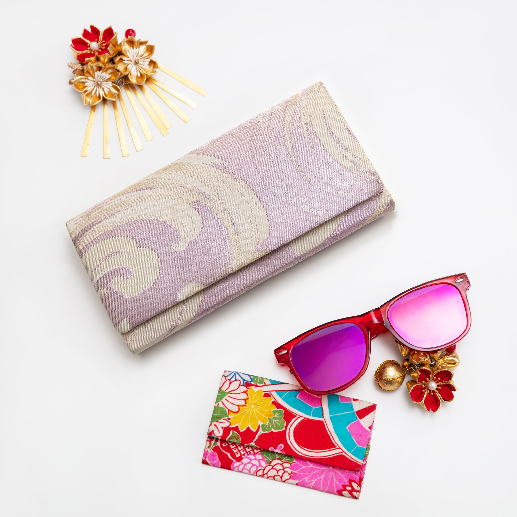 Vintage Japanese fold over clutch bag in lilac with wave pattern on white background and surrounded by accessories.