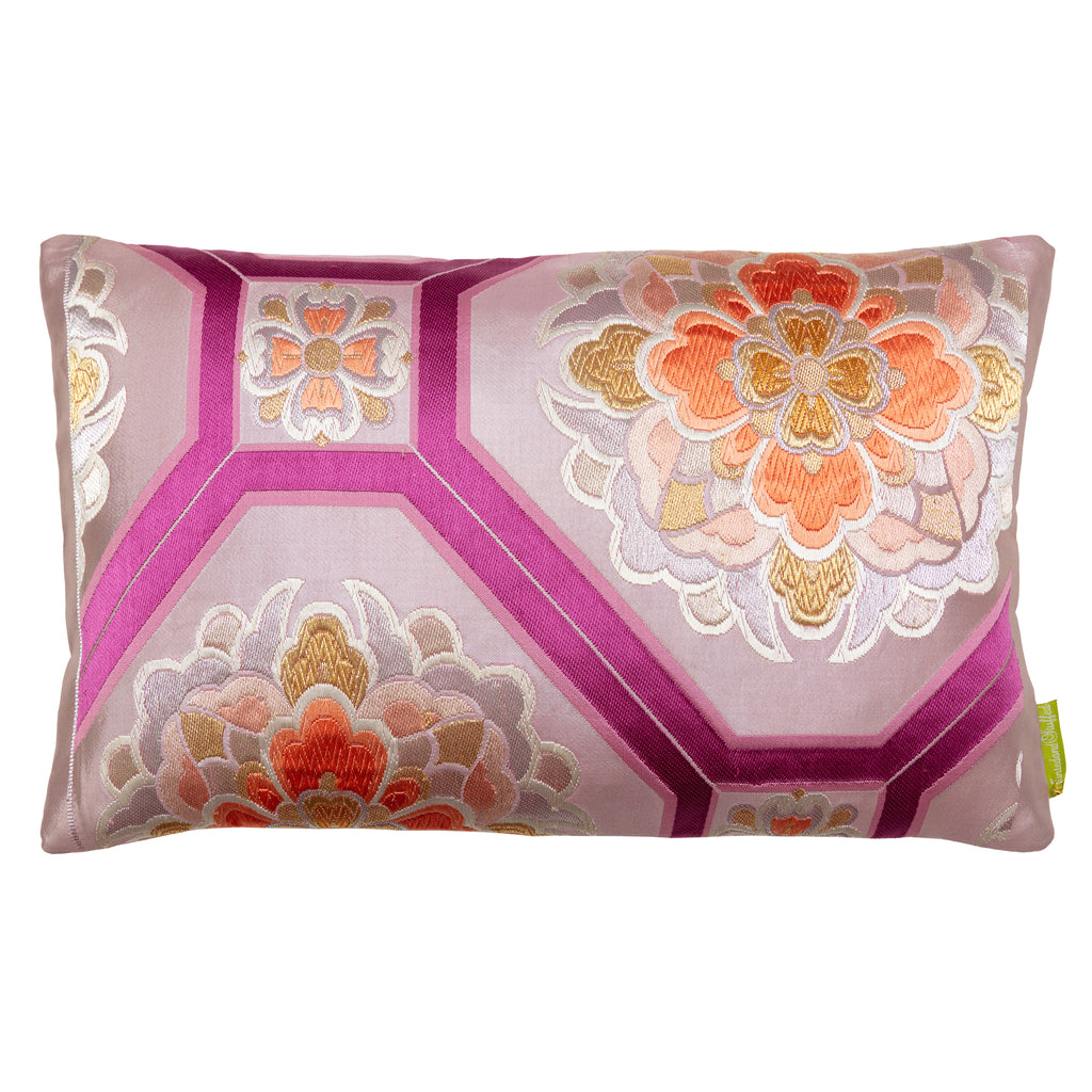 A decorative silk Japanese obi pillow with a geometric pattern and floral designs, featuring colors such as pink, mauve, purple, orange, silver, and gold.