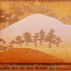 Close up of vintage kimono silk clutch with bronze, gold and orange metallic mountain and tree pattern.