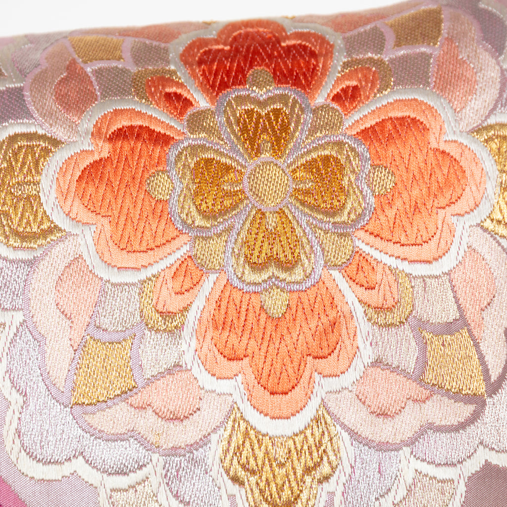 close up of the vintage silk obi cushion showing the orange and gold hanabishi flower pattern embroidery