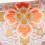 close up of the vintage silk obi cushion showing the orange and gold hanabishi flower pattern embroidery