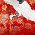 close up of vintage kimono silk showing white crane over red and gold flowers