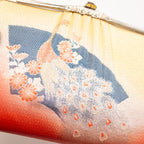 View of the main design on the front of the vintage Japanese silk clutch bag showing patterned silk in geometric pattern, black fan shape and peacock in gold.