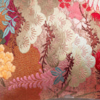 Close-up of the vibrant red fabric with detailed crane and floral embroidery showcasing the textured lilac velvet accents on