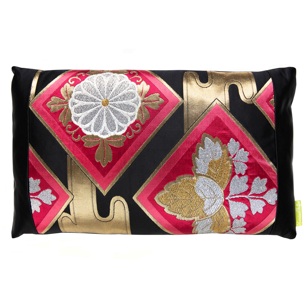 A rectangular throw pillow with a black silk base featuring a pink floral motif and metallic gold accents in a geometric pattern. Made from vintage Japanese obi silk.