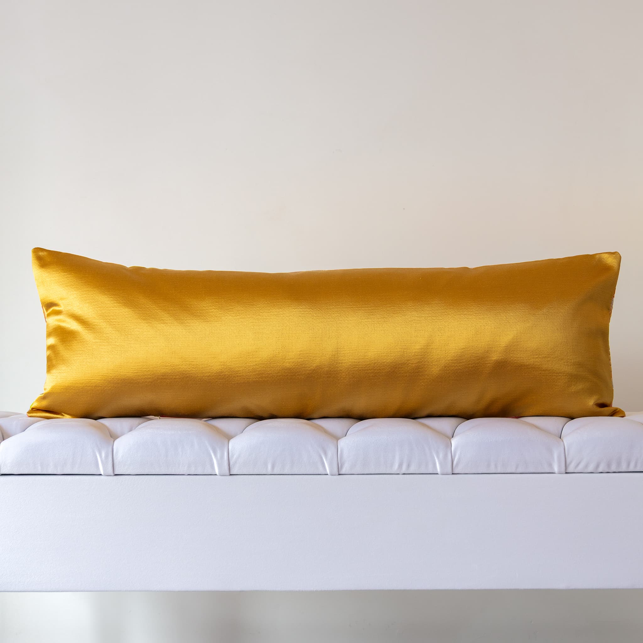 Reverse of pink silk bolster cushion in hammered gold designer satin