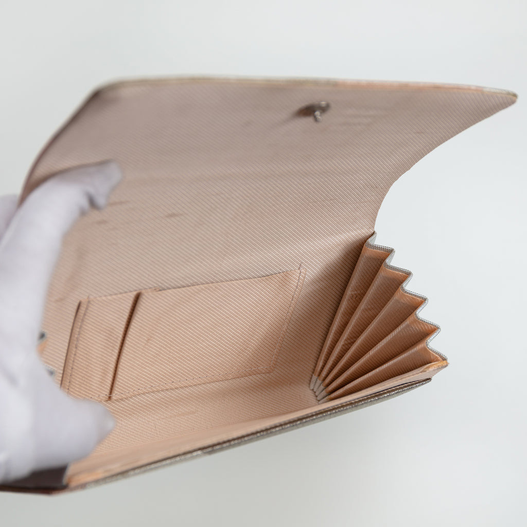 Internal view of vintage Japanese silk clutch bag showing pink silk lining and internal pocket. Held open by a gloved hand.