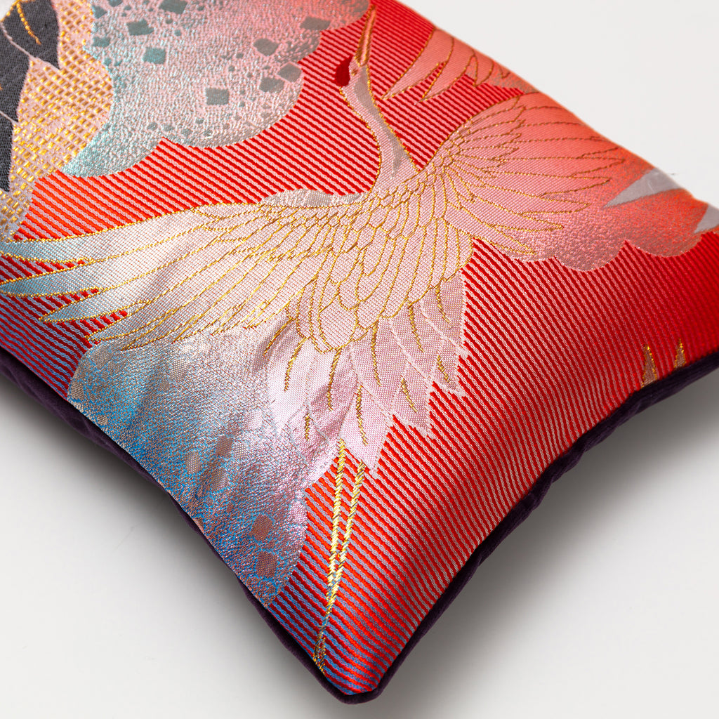 Close-up of the rich crimson silk fabric with visible intricate crane embroidery and subtle purple velvet sheen on the