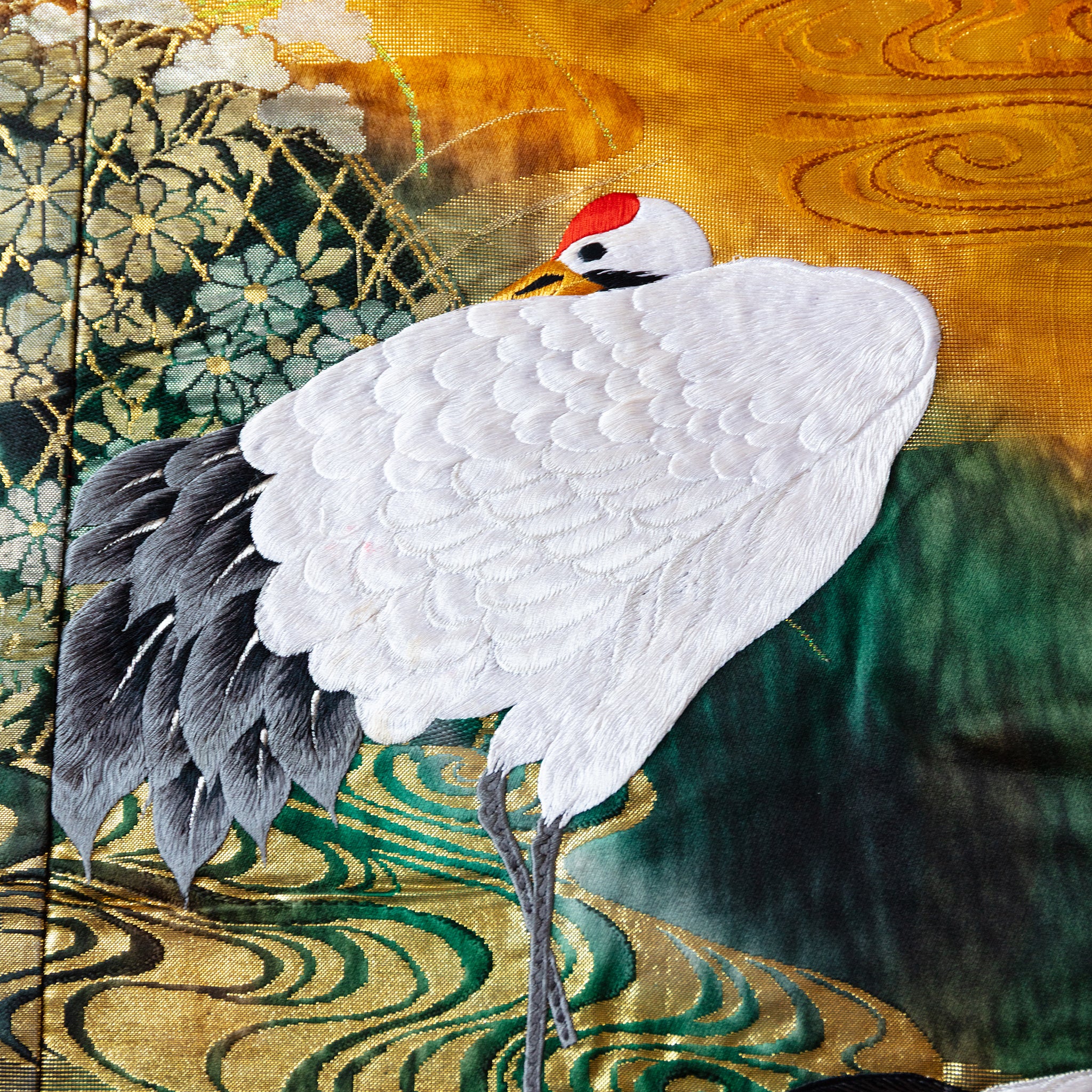 close up of vintage kimono silk showing crane and swirling water detail in white, green and gold