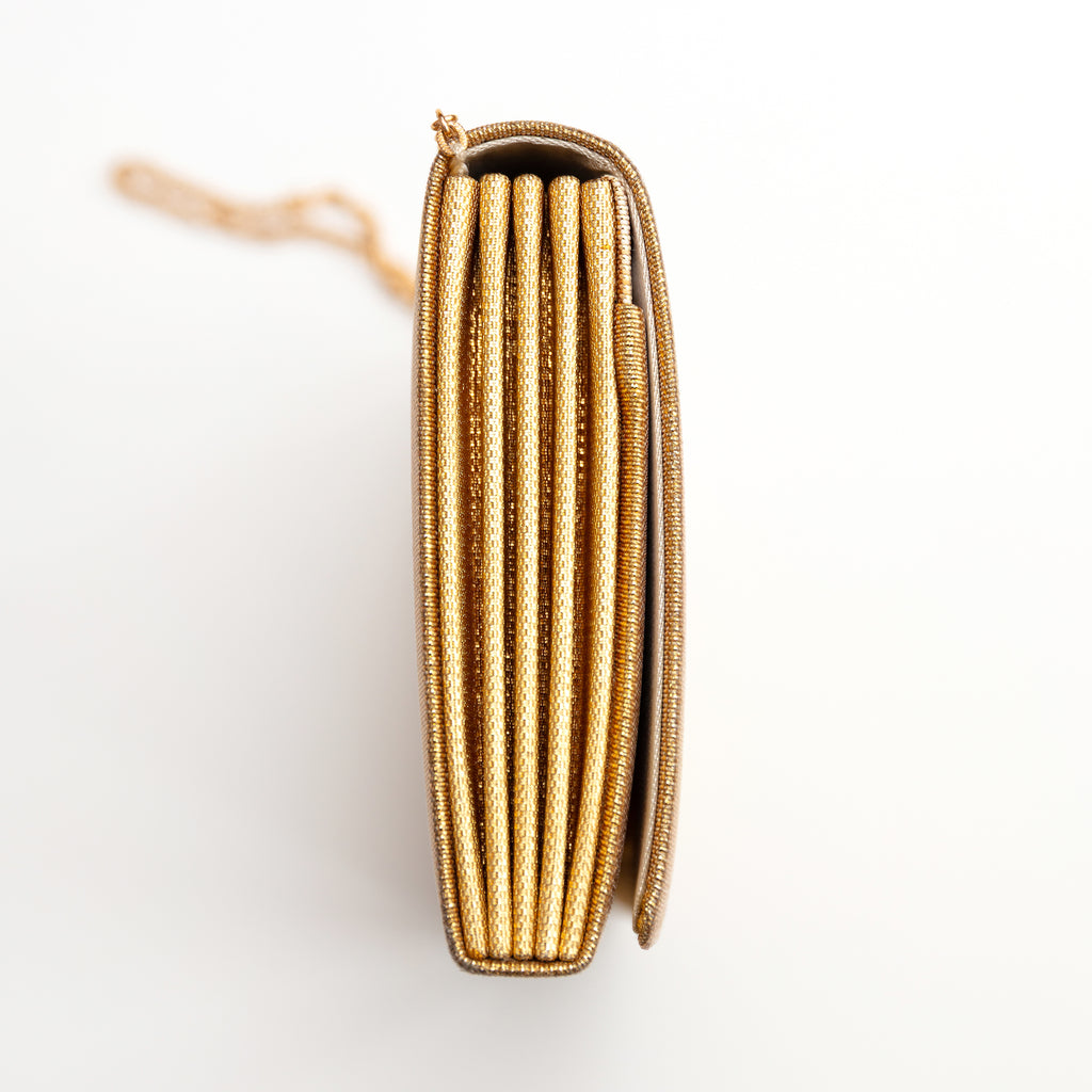 Side view of a vintage Japanese gold clutch bag showing the concertina style folded side panel in metallic gold.