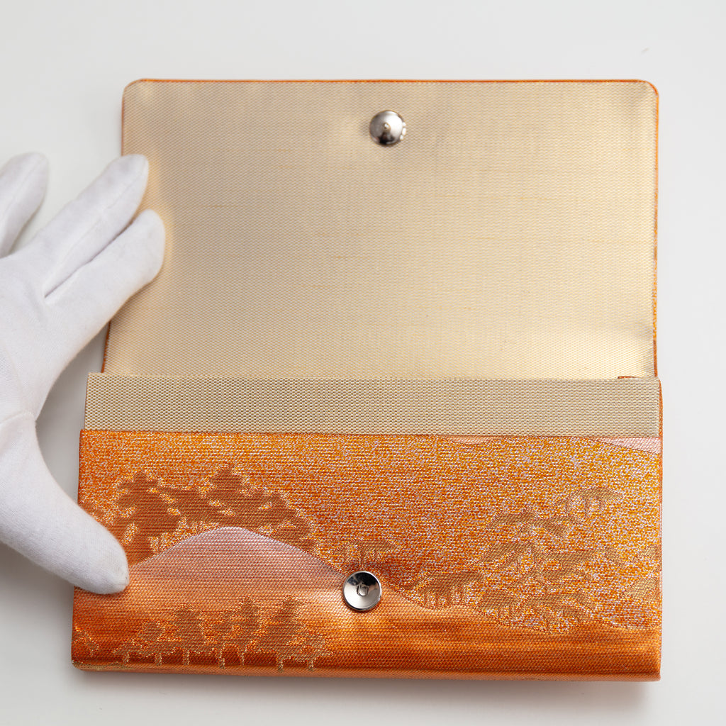 Vintage Japanese silk clutch bag being held open by a gloved hand to show the silk lining and metal clasp.