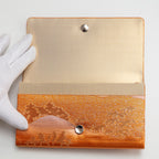 Vintage Japanese silk clutch bag being held open by a gloved hand to show the silk lining and metal clasp.