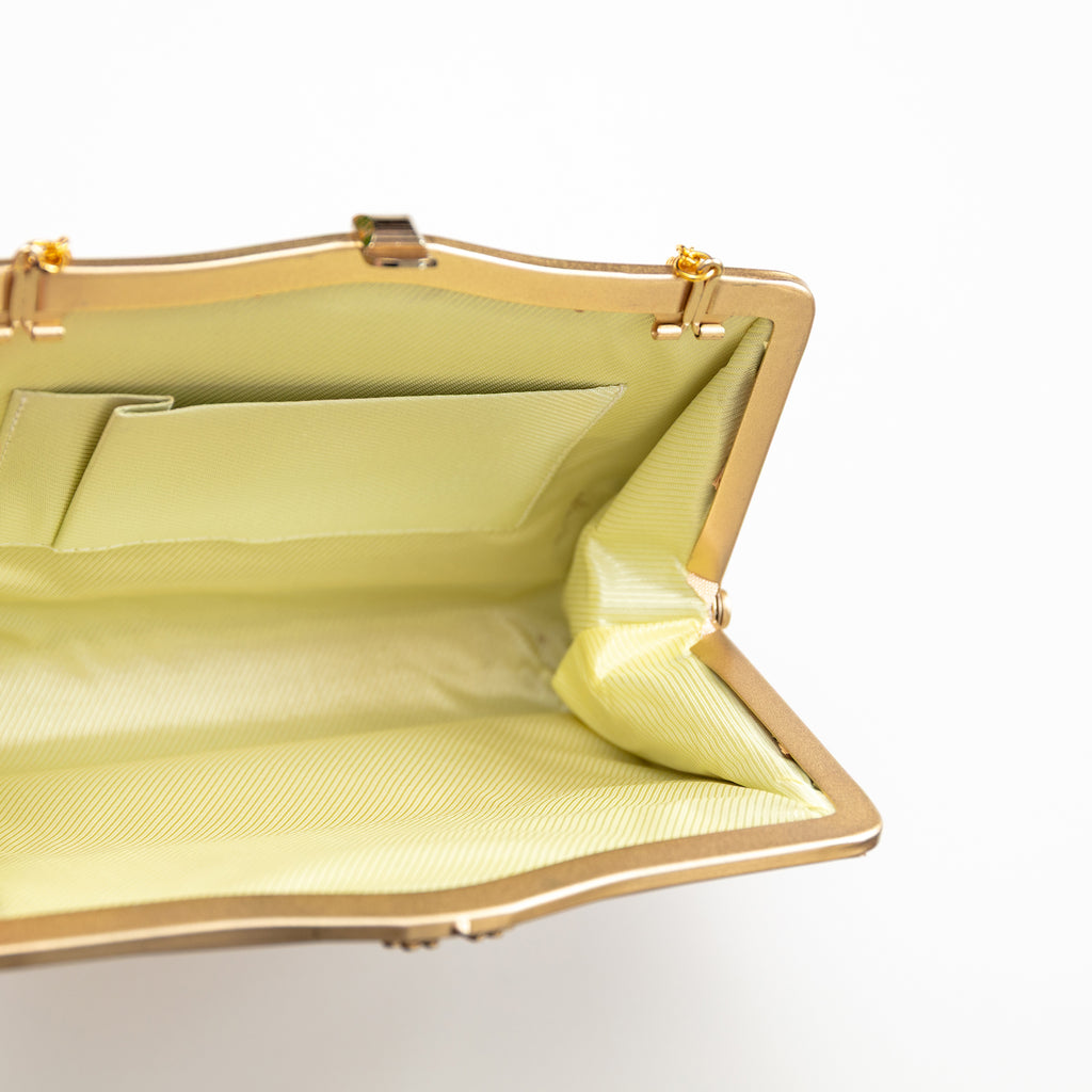 Inside view of vintage Japanese silk clutch bag in gold, with cream silk lining, internal pocket and gold metal frame.