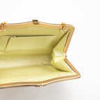 Inside view of vintage Japanese silk clutch bag in gold, with cream silk lining, internal pocket and gold metal frame.