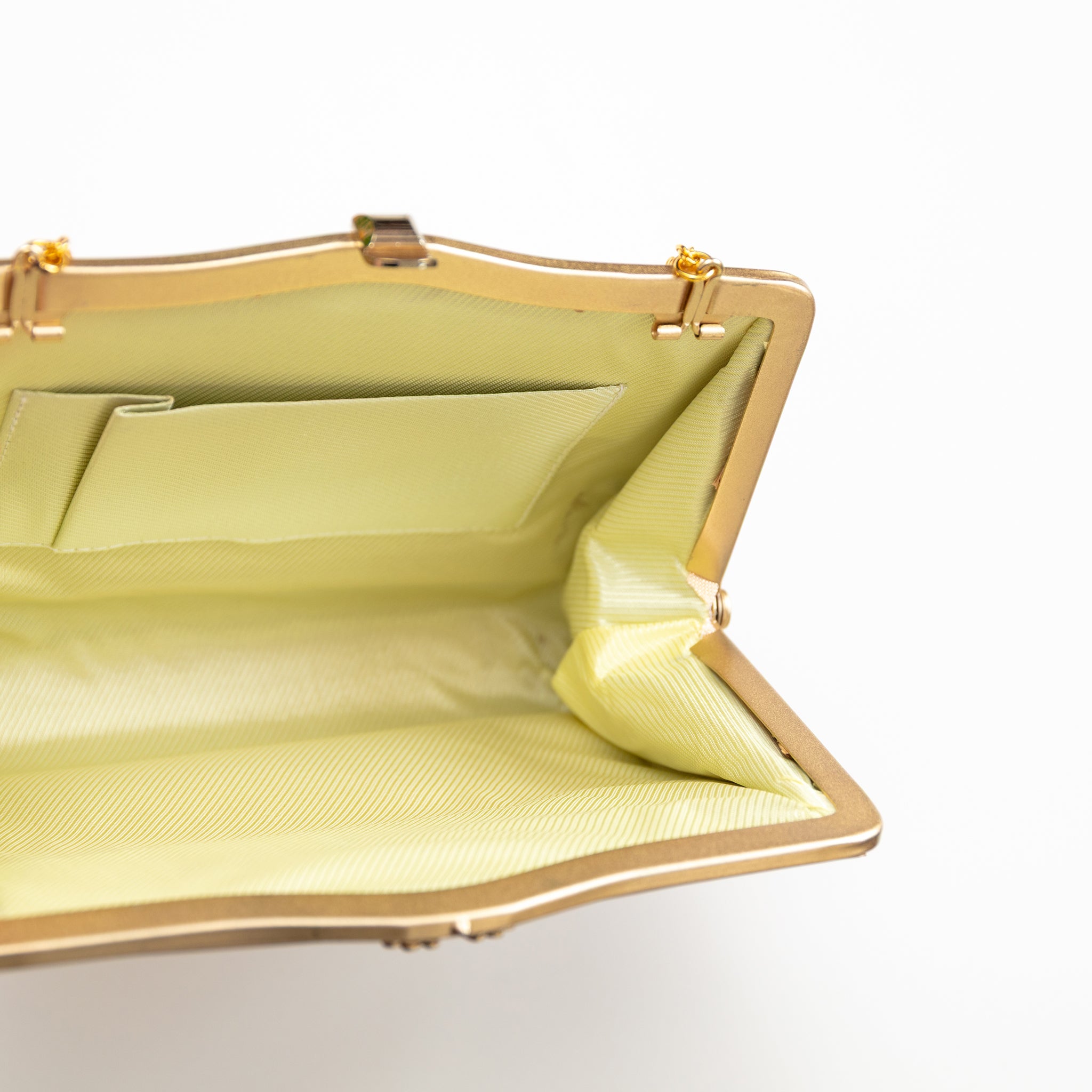 Inside view of vintage Japanese silk clutch bag in gold, with cream silk lining, internal pocket and gold metal frame.