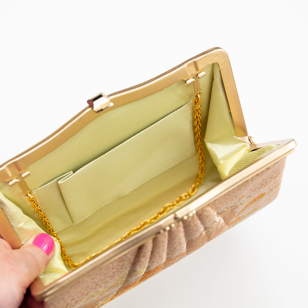 Interior of vintage Japanese silk clutch bag showing cream silk lining, internal pocket and gold chain strap tucked inside.
