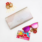 Silver metallic vintage Japanese silk clutch bag on white with accessories and sunglasses.