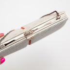 Detail view of the ornate silver clasp on a vintage Japanese silk clutch bag in white and silver. 