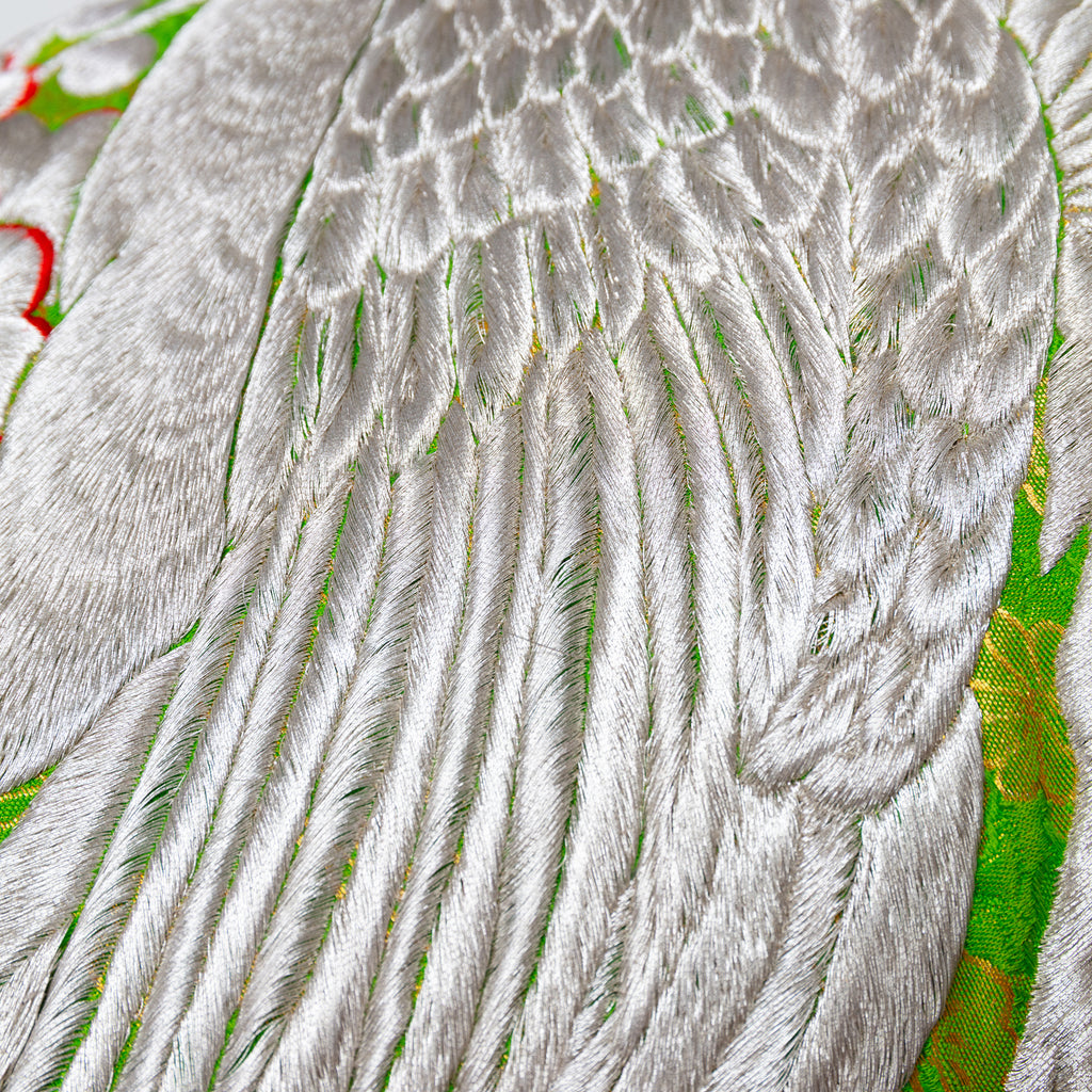 Close-up of silver blossom embroidery and snowdrift satin back fabric detail on the green silk kimono pillow, showcasing