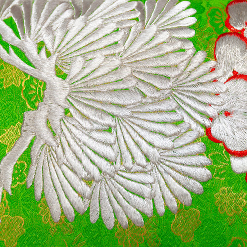 Close-up of the Green Silk Kimono Pillow's silver blossom embroidery over woven green and gold silk base with flower motifs.
