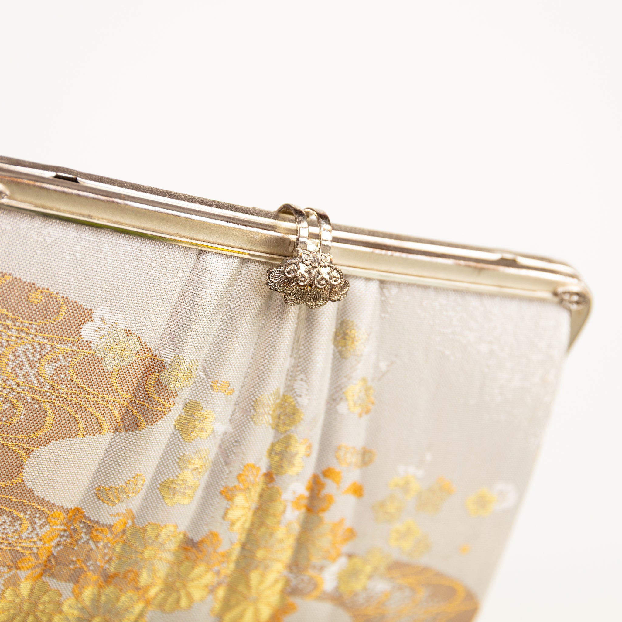 Detail shot of the filigree silver clasp on cream vintage Japanese clutch bag and the pleated structure detail on the front of the bag