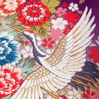 close up of silk cushion made from vintage kimono silk showing flying crane over red and blue flowers on purple