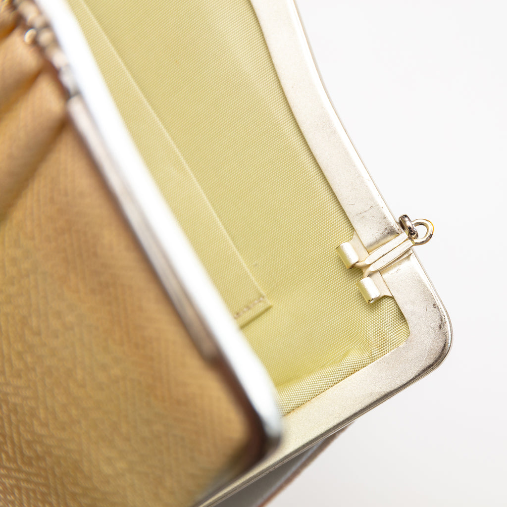 Close up of a vintage Japanese silk clutch bag top right corner, the bag is open, focus is on the silver hinge for the chain strap which can tuck in or out of the bag.