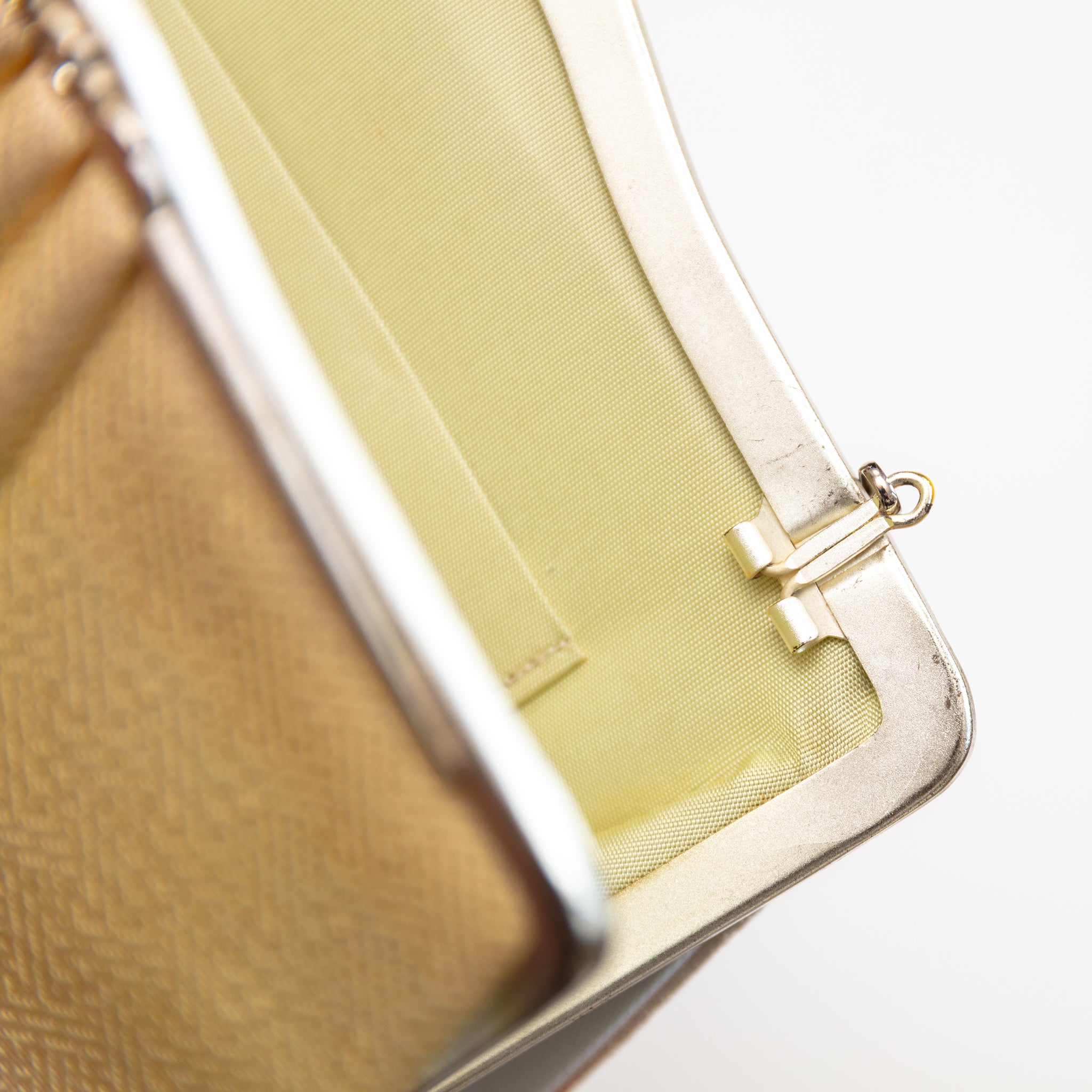 Close up of a vintage Japanese silk clutch bag top right corner, the bag is open, focus is on the silver hinge for the chain strap which can tuck in or out of the bag.