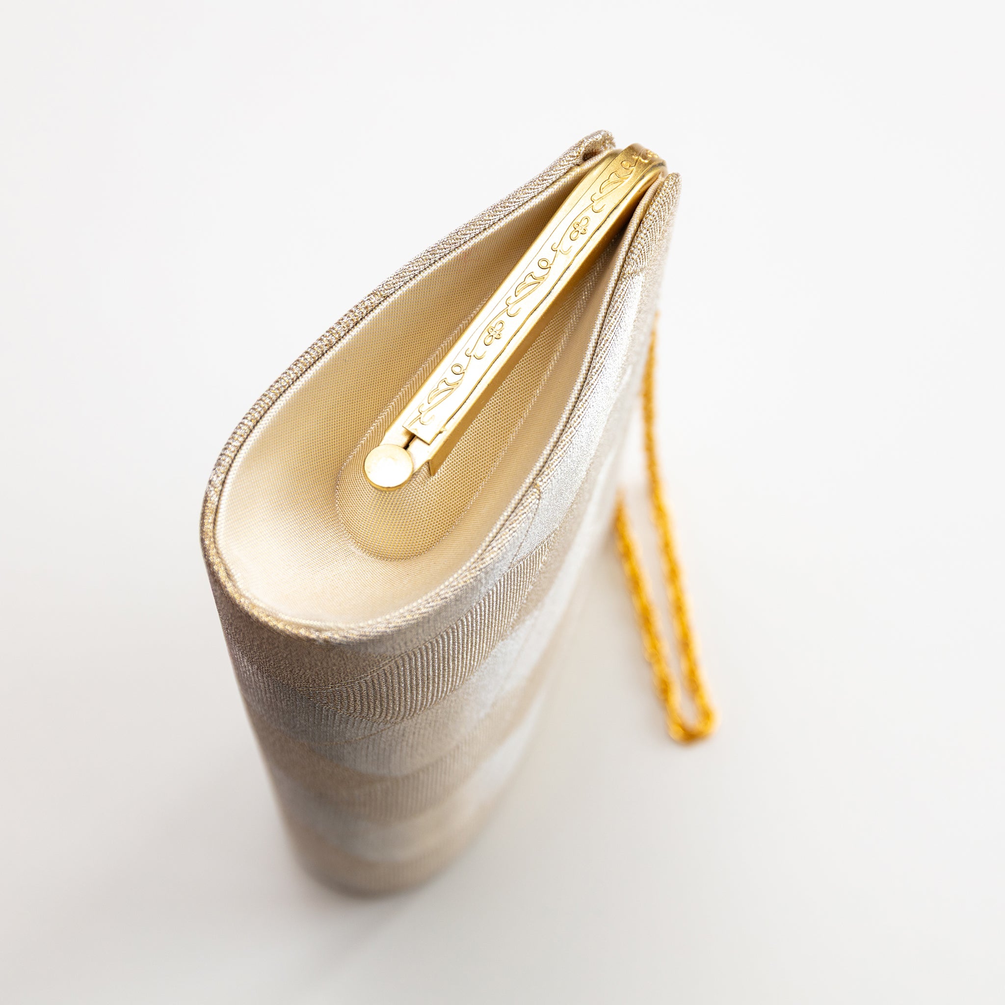 Side view of vintage Japanese silk clutch  bag in gold, showing pattern on gold frame and gold chain strap
