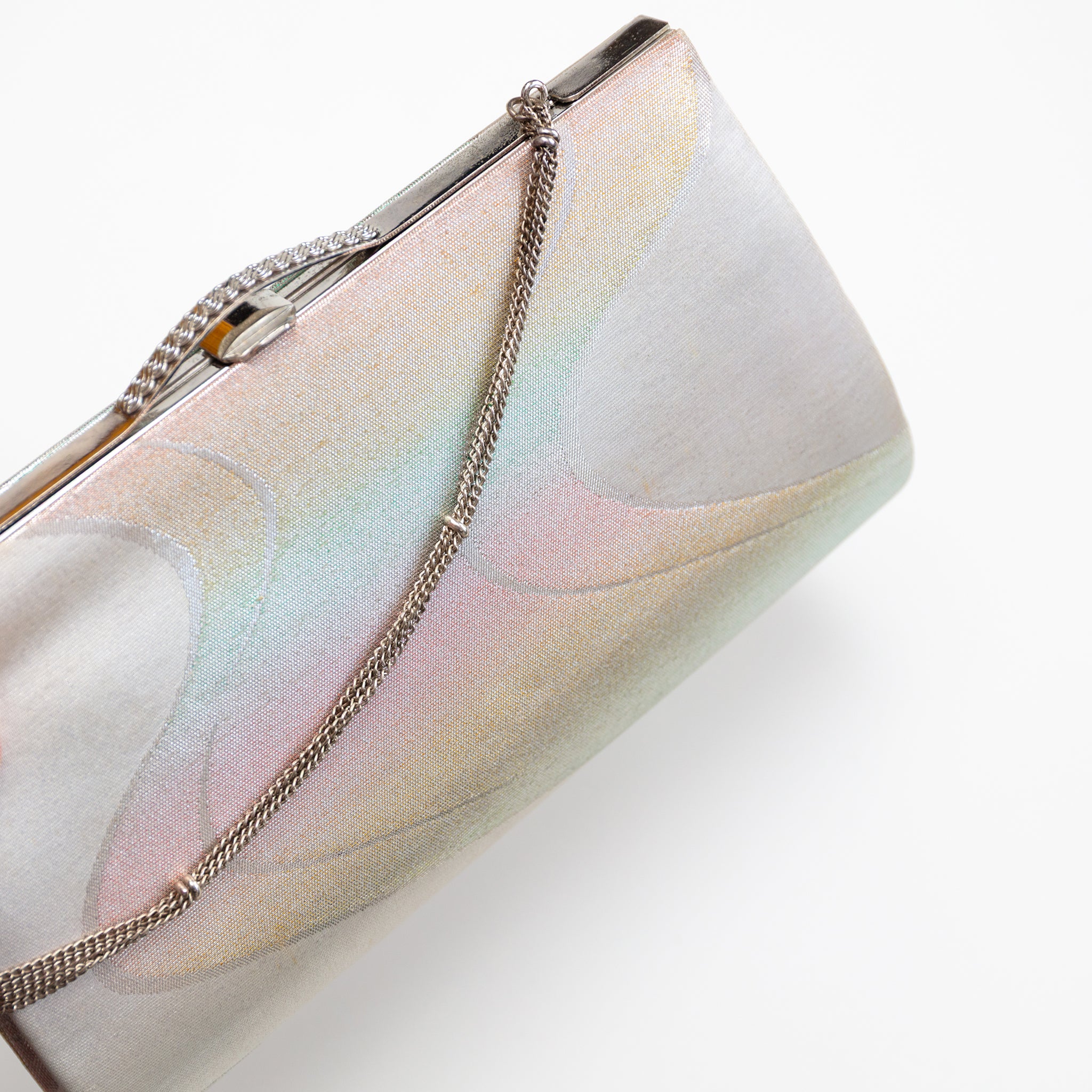 Close up of vintage Japanese clutch bag in iridescent silver silk with river pattern. The bag is closed and the decorative silver chain strap drapes over the front of the bag.