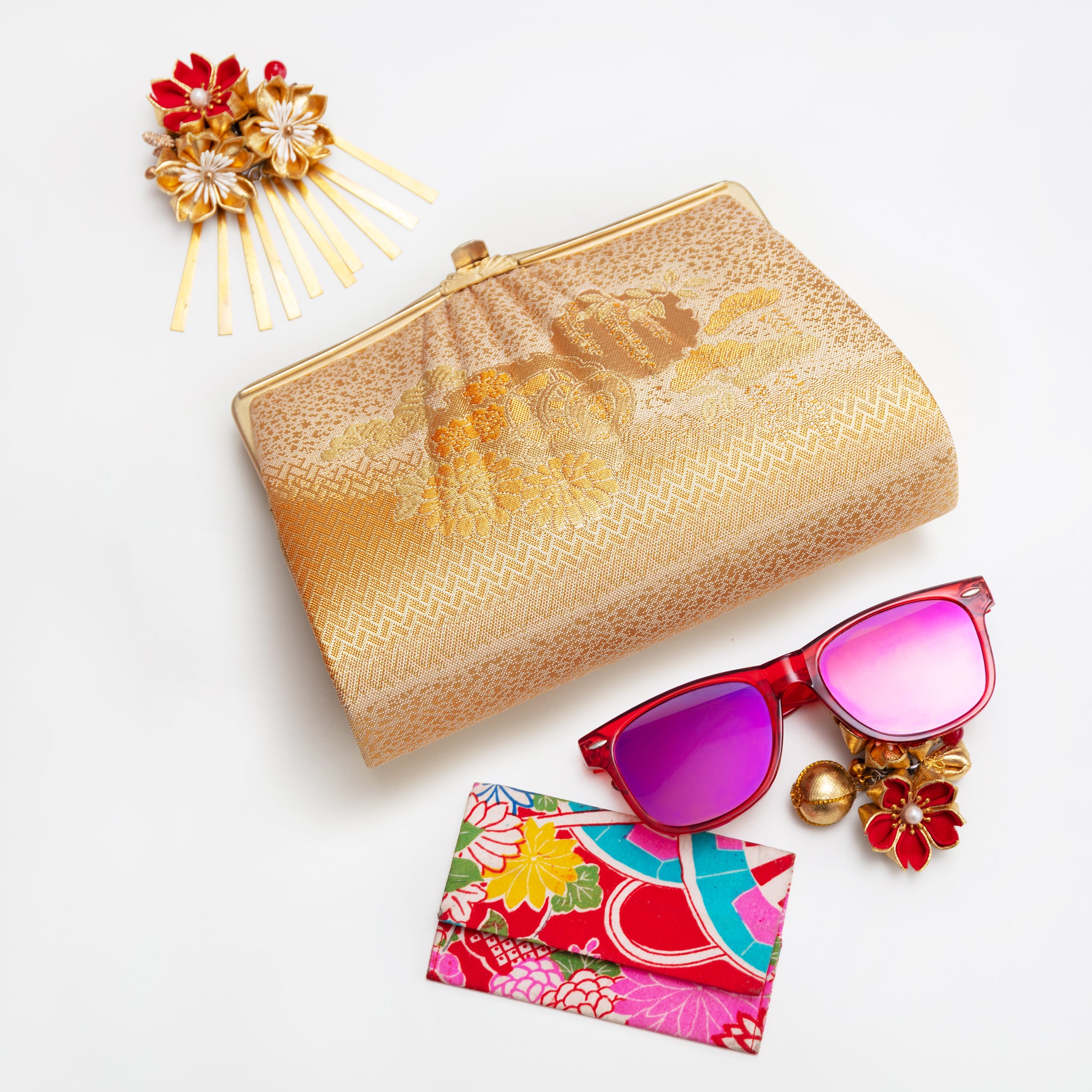 Vintage Japanese silk clutch bag with gold flowers and clasp on a white background with colourful accessories