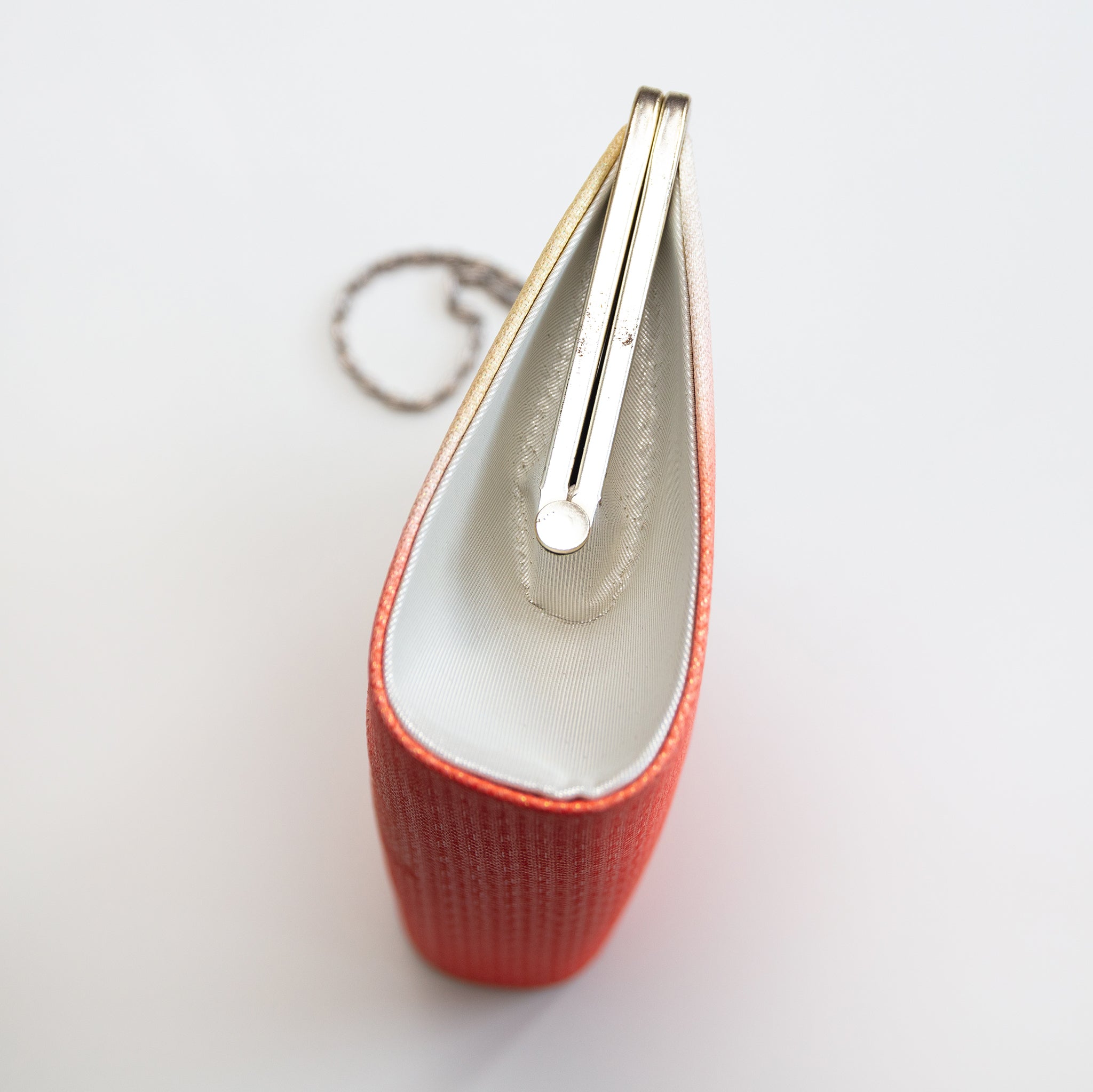 Side view of a vintage Japanese silk clutch bag with silver side panel in silk and the silver bag frame closed.
