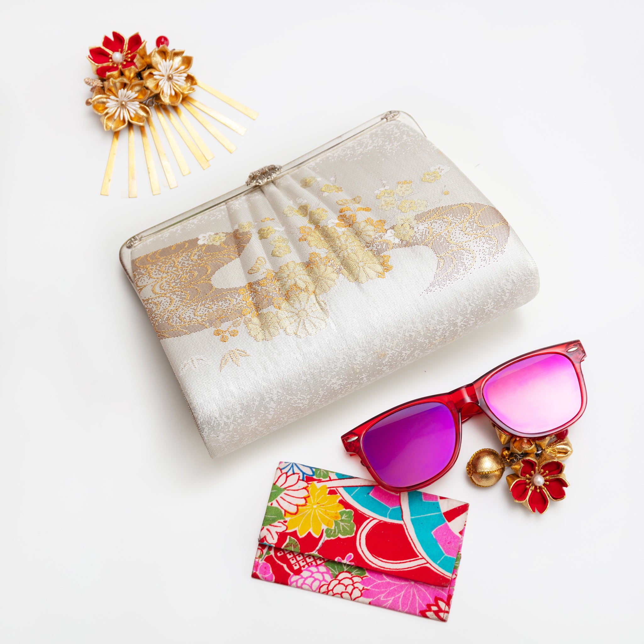 Vintage Japanese silk clutch  bag in white and gold, floral river pattern, on neutral surface with accessories