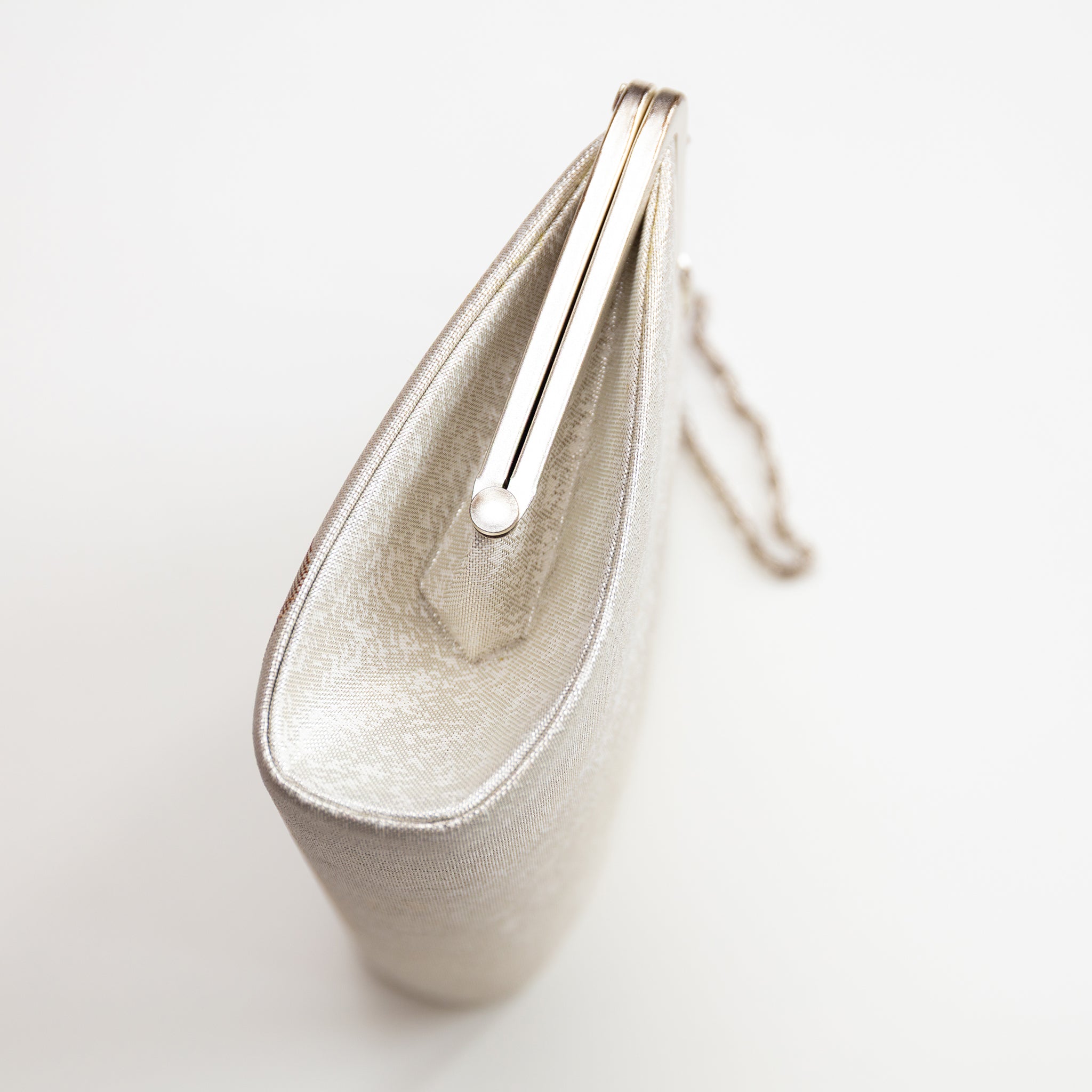 Side view of vintage Japanese silk clutch bag showing structured shape and silver metal frame